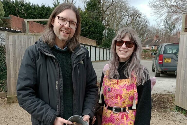 A man and woman stood holding a plant pot