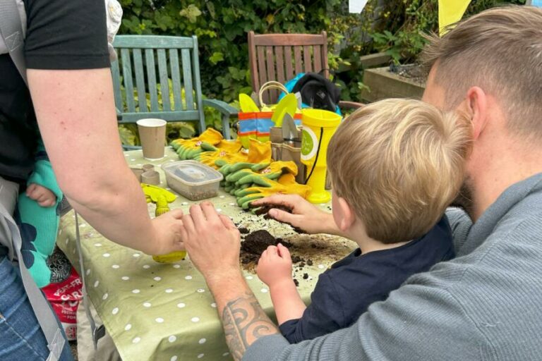 A family sat at a bench potting seeds in soil