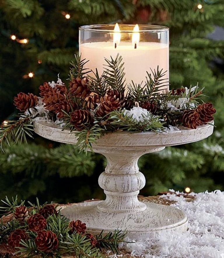 A table centerpiece featuring a candle, pine cones and greenery