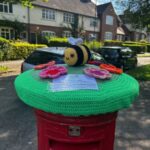 A crochet bee on top of a red postbox