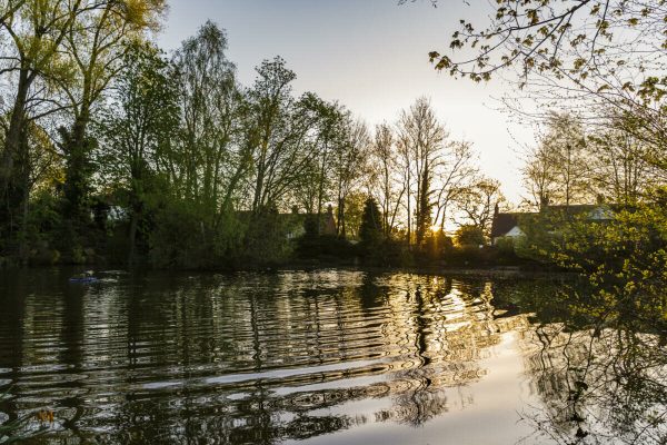 Moor Pool pond with the sun low in the sky and ripples across the water