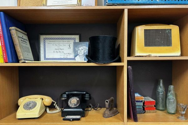 Shelves holding vintage telephones, bottles, a radio and books